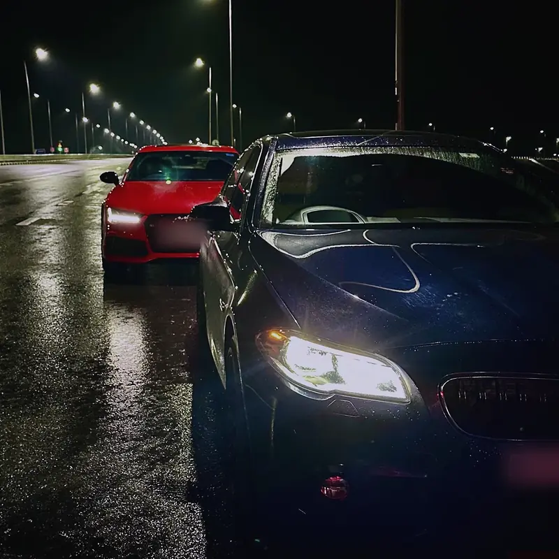 Wet tarmac, streetlights and two performance cars at night