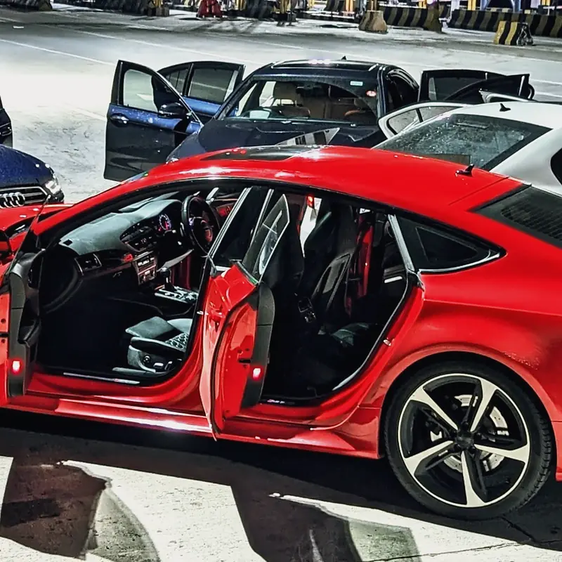 Open doors and bucket seats of a red Audi RS7 at night
